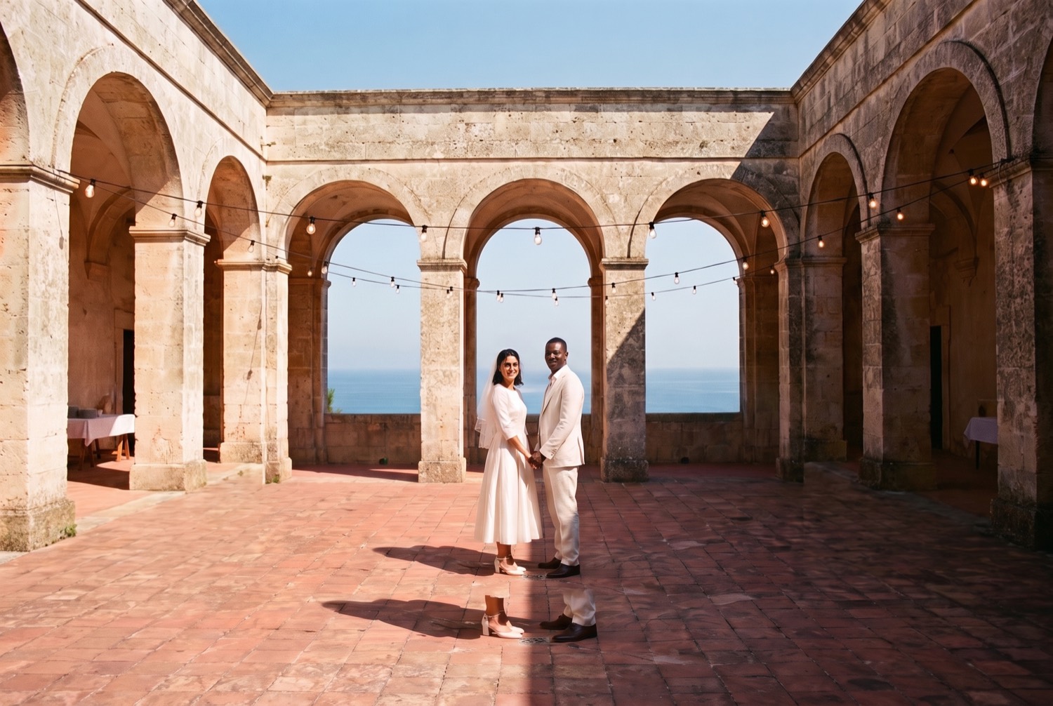 The same photo widened to a landscape frame, showing more of the courtyard arches and the sea.